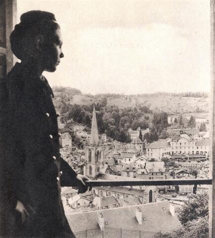 Photo noir et blanc d'un enfant de troupe près d'une fenêtre avec vue sur les toits de Tulle