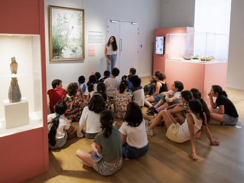 Un groupe d'élèves assis en salle d'expo devant un tableau