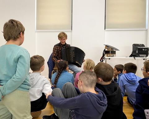 Un groupe d'élève devant un accordéoniste